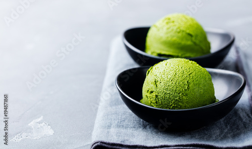 Matcha ice cream scoop in bowl on a grey stone background. Copy space.