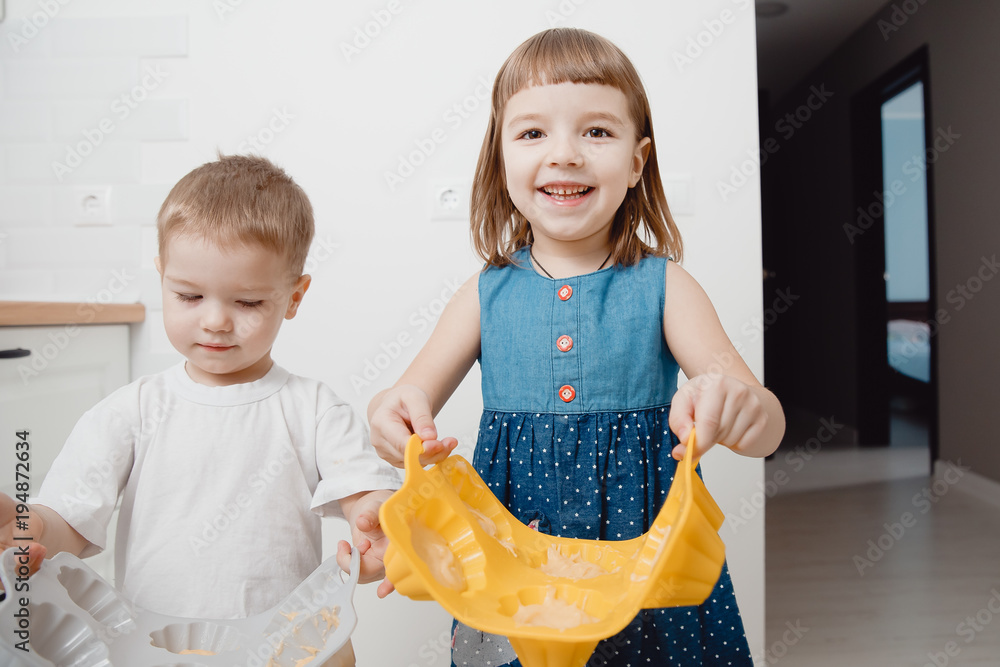 Children are holding cupcake molds in their hands, they are preparing to place the baking in the oven. Smile and laugh. The concept of family cooking. Children are holding cupcake molds in their hands, they are preparing to place the baking in the oven. Smile and laugh. The concept of family cooking.