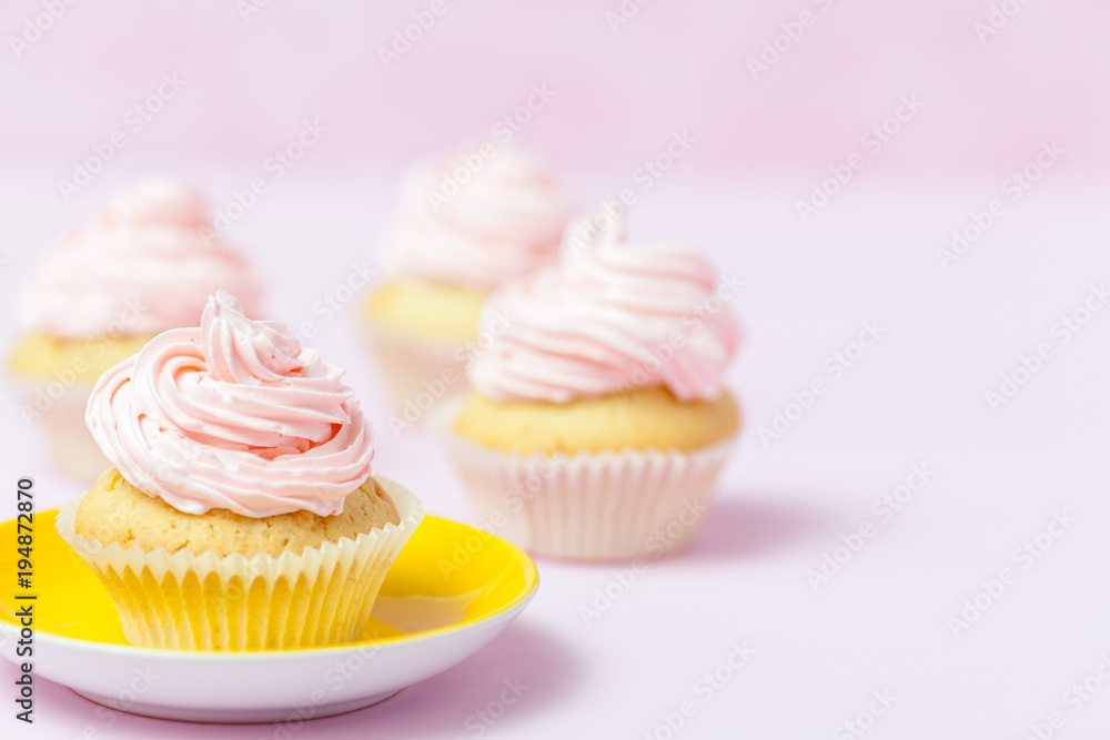 Cupcake decorated with pink buttercream in bright yellow plate on pastel pink background. Sweet beautiful cake. Horizontal banner, greeting card, congratulation. Close up photography. Selective focus Cupcake decorated with pink buttercream in bright yellow plate on pastel pink background. Sweet beautiful cake. Horizontal banner, greeting card, congratulation. Close up photography. Selective focus