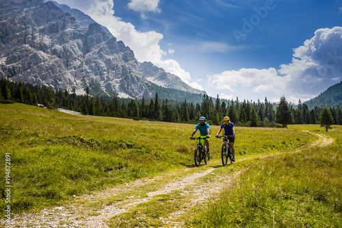 Cycling couple with bikes on track, Cortina d'Ampezzo, Dolomites, Italy