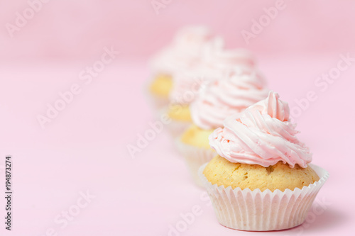 Cupcake decorated with pink buttercream on pastel pink background. Sweet beautiful cake. Horizontal banner, greeting card for birthday, wedding, women's day. Close up photography. Selective focus