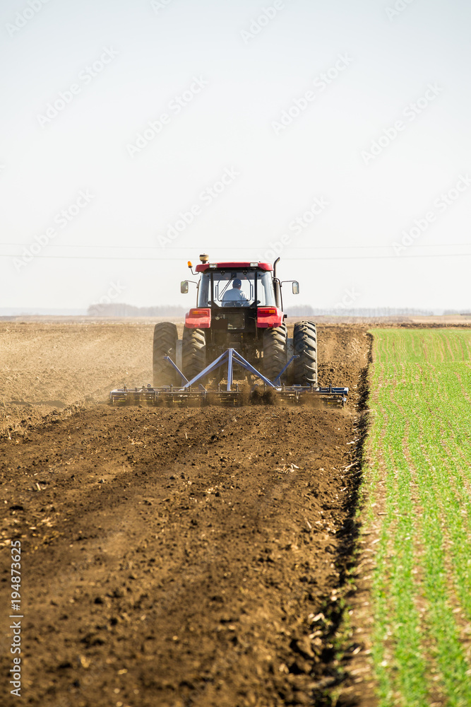 Fototapeta premium Farmer in tractor preparing land with seedbed cultivator as part of pre seeding activities in early spring season of agricultural works at farmlands.