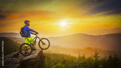 Mountain biker riding at sunset on bike in summer mountains forest landscape. Man cycling MTB flow trail track. Outdoor sport activity.