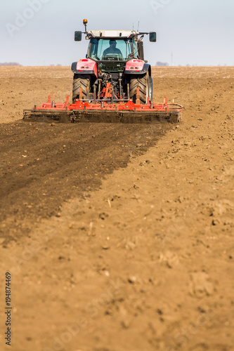 Farmer in tractor preparing land with seedbed cultivator as part of pre seeding activities in early spring season of agricultural works at farmlands. © oticki
