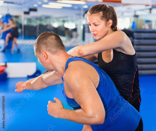 Woman is training captures with man on the self-defense course in gym.