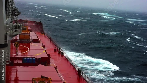 Cargo ship sailing through violent storm. Wind speed 11 as per Beaufort scale. Very large patches of foam, driven before the wind, cover much of the sea surface. Oct, 2017. Pacific, Japanese coast photo