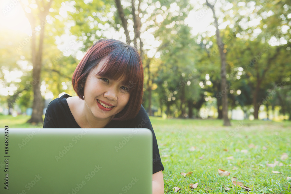 Young asian woman's legs on the green grass with open laptop. Girl's hands on keyboard. Distance learning concept. Happy hipster young asian woman working on laptop in park. Student studying outdoors. Young asian woman's legs on the green grass with open laptop. Girl's hands on keyboard. Distance learning concept. Happy hipster young asian woman working on laptop in park. Student studying outdoors.