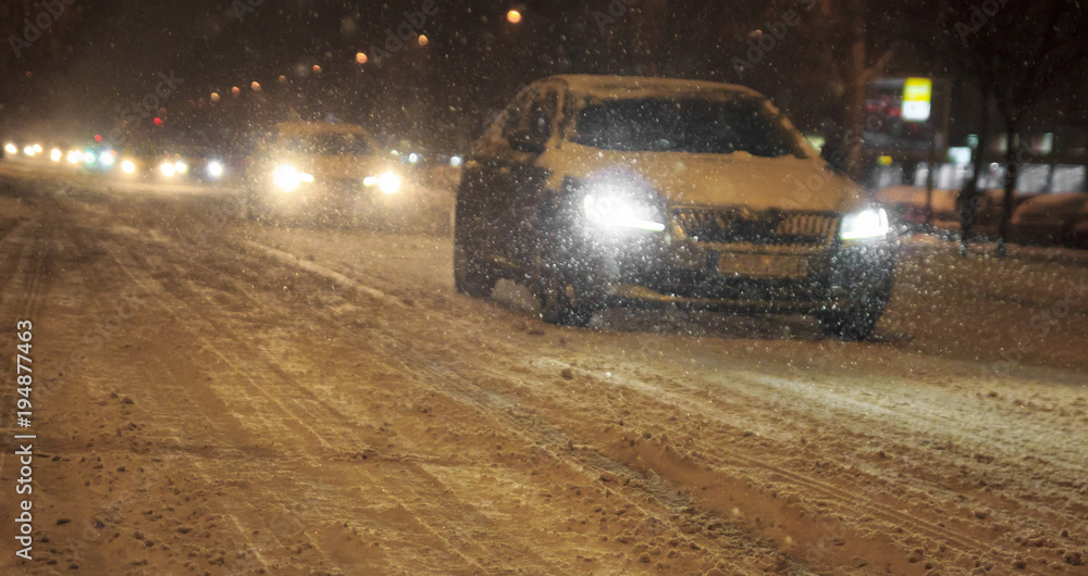 Obraz premium Traffic in the city cars bad weather and snow fall blizzard by night