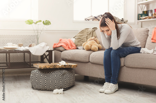 Quadro em tela Desperate woman sitting on sofa in messy room