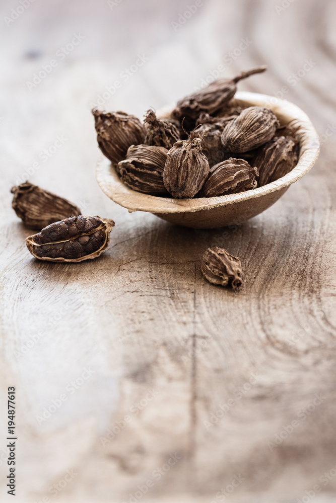 Black cardamom in a bowl on wooden background Black cardamom in a bowl on wooden background