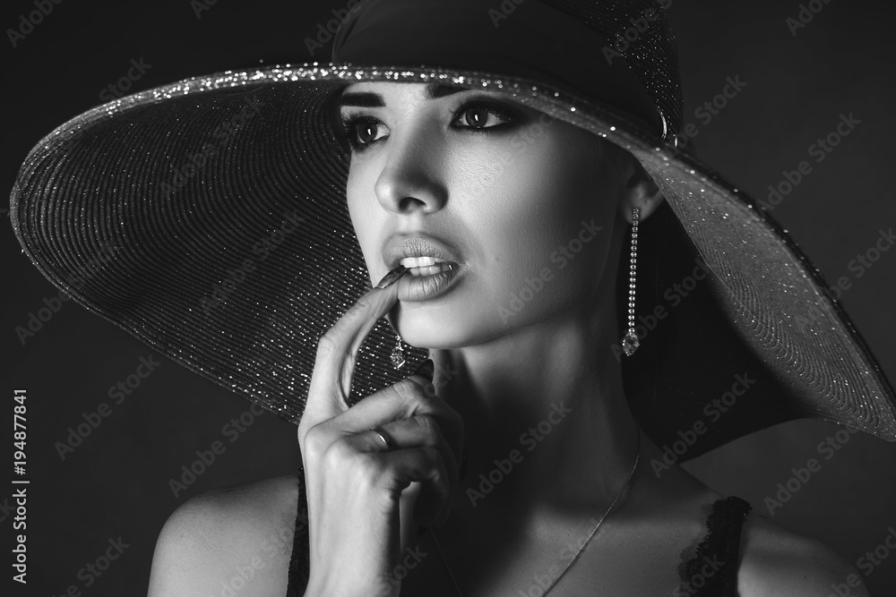 Fototapeta styl glamour. Piękny portret kobiety w kapeluszu na czarnym tle, czarno-białe zdjęcie