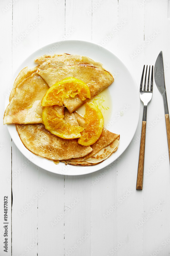 Overhead image of pancakes with orange confiture in white plate on wooden table