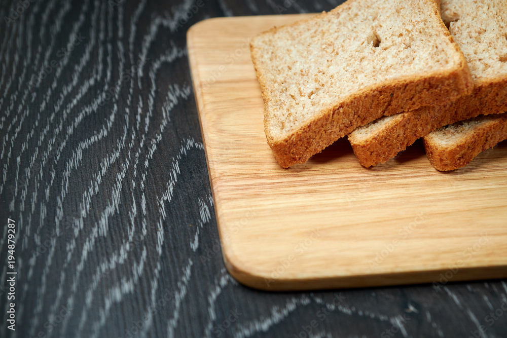 Sliced bread on wooden cutting Board, on dark wooden background, bran Sliced bread on wooden cutting Board, on dark wooden background, bran