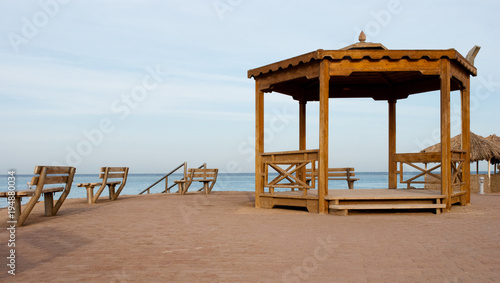 alcove and benches on the beach. Big wooden alcove and two benches on sand shore. Empty place for meeting near sea.
