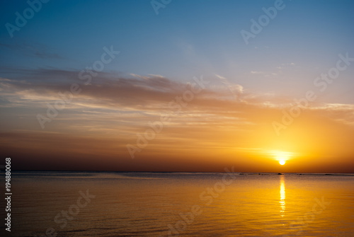 Yellow sunrise on the ocean. Sun under the red sea in the morning. Sunset and reflex on water in the evening. Golden Sunrise and blue sky.