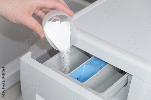 Foto hand falls asleep washing powder in the compartment of the washing machine