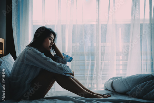 Fotografie, Obraz Asian woman sitting on a bed looking sad
