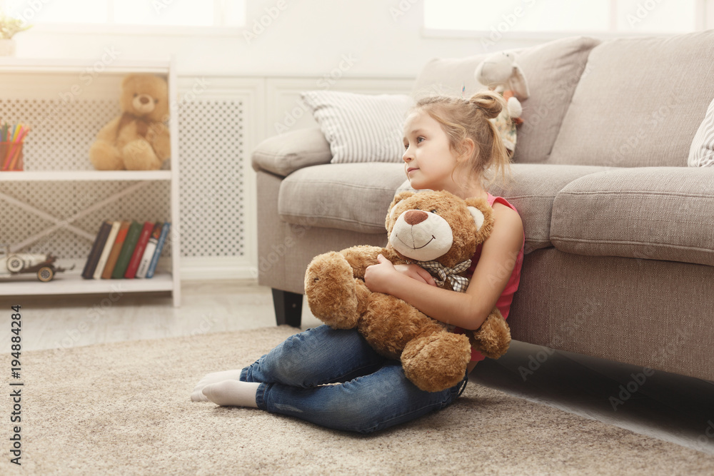 Happy little female child hugging her teddy bear on the floor at home Happy little female child hugging her teddy bear on the floor at home