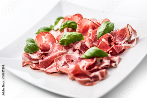 Prosciutto. Curled slices of delicious Italian Prosciutto with basil