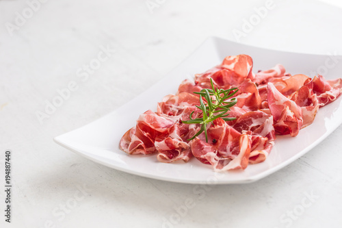 Prosciutto. Curled slices of delicious italian prosciutto with r