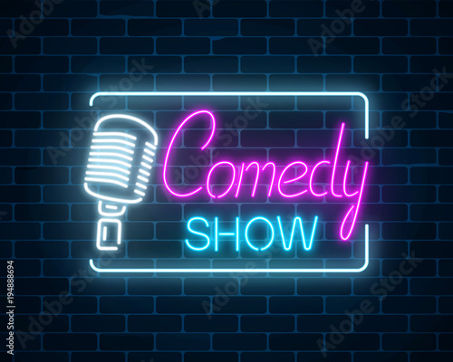 Neon sign of comedy show with retro microphone symbol on a brick wall background. Humor glowing signboard.