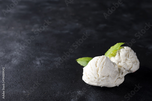 vanilla ice cream ball with green leaves on dark photo