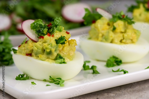 Obraz na płótnie Boiled eggs stuffed with avocado paste with parsley, chili and radish - healthy