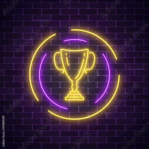 Glowing neon sign with award cup in round frame on dark brick wall background. Winner cup honorary trophy