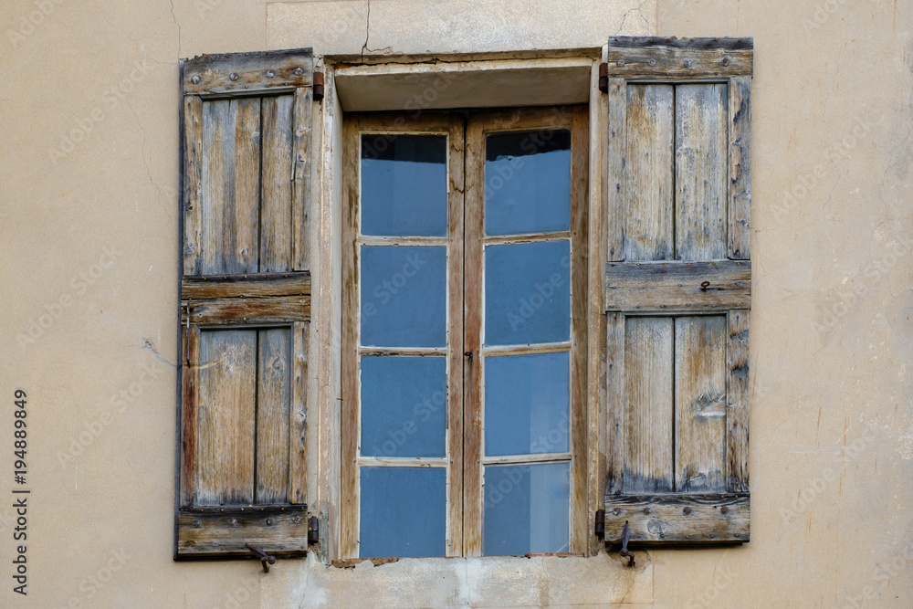 Vieille fenêtre avec des volets en bois sans peinture.