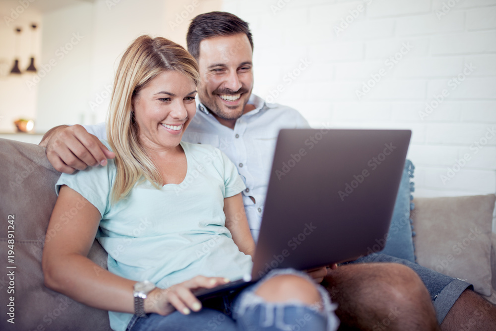 Couple relaxing together on sofa and using a laptop computer.