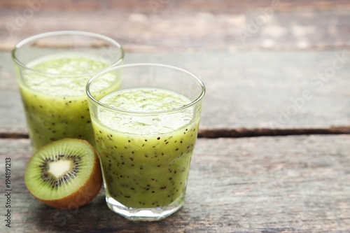 Fresh kiwi smoothie in glass on grey wooden table