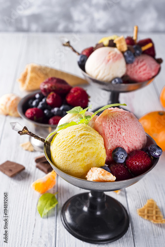 Fototapeta Naklejka Na Ścianę i Meble -  Bowl with ice cream with three different scoops of yellow, red colors and waffle cone, chocolate,