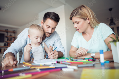 Mom  dad and son draw in the living room.