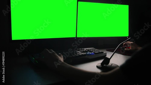 working with two monitors in dark, green screen photo