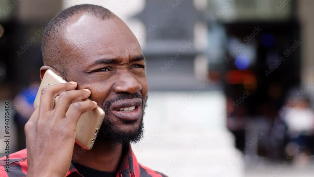 black man focused in a telephone conversation in the street black man focused in a telephone conversation in the street