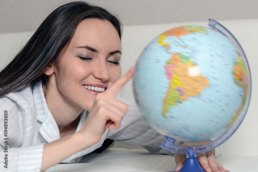 Search for adventure. Closeup of a smiling woman in pajamas rotate the globe with your eyes closed Search for adventure. Closeup of a smiling woman in pajamas rotate the globe with your eyes closed