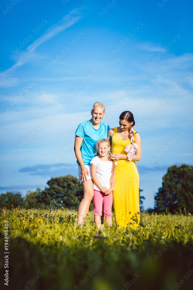 Two women with child on a meadow being playful