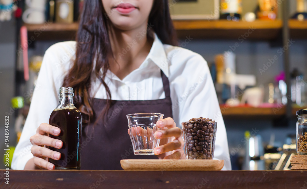 Girl barista bartender waiter in uniform making coffee, Girl barista bartender waiter in uniform making coffee,Asian Barista woman Cold brew coffee in glass bottle to a cup glass in the coffee shop. p