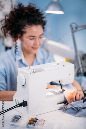 large beads and colorful buttons in front of motion blur image of tailor and sewing machines. useful tools for seamstress. decorating clothers. photo