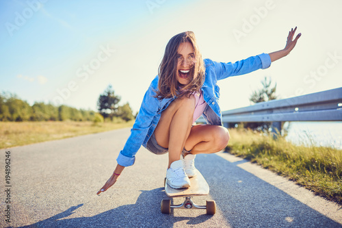 Beautiful girl balancing on longboard and screaming in joy