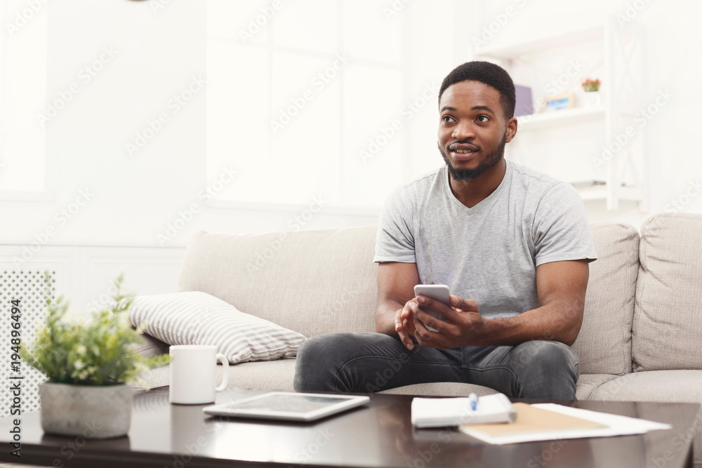 Smiling young man at home messaging on mobile Smiling young man at home messaging on mobile