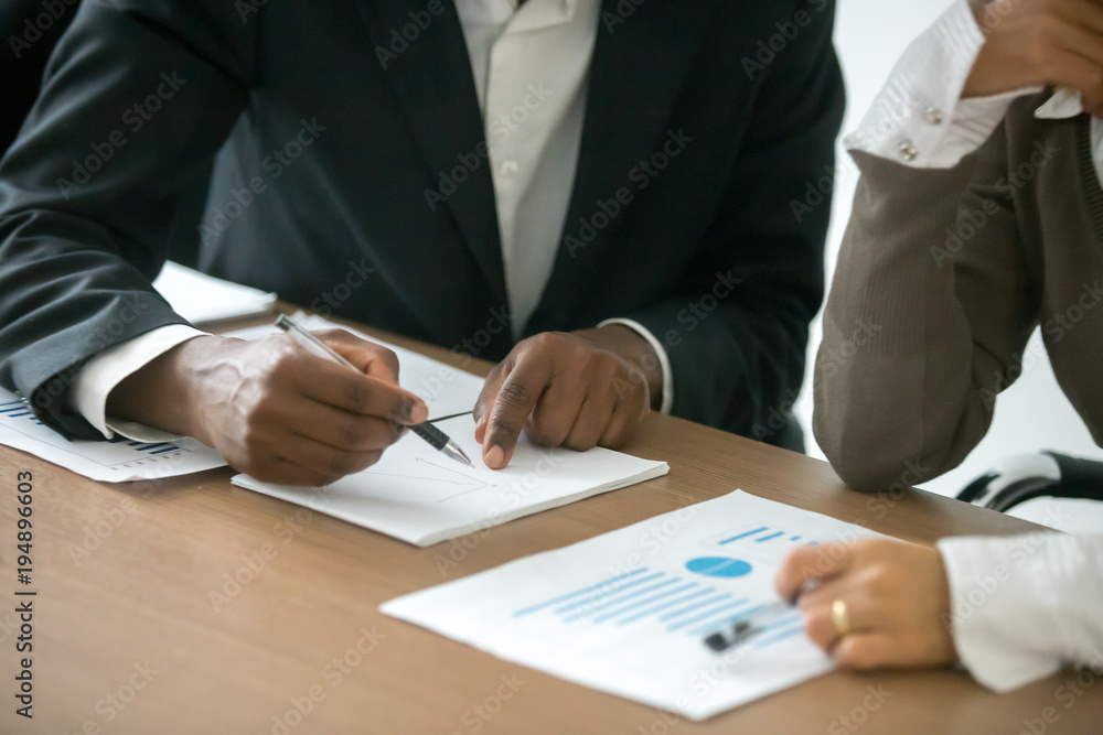 Diverse businessman and businesswoman working together with statistics, african man drawing graph explaining new idea for business improvement to caucasian colleague, project team teamwork concept Diverse businessman and businesswoman working together with statistics, african man drawing graph explaining new idea for business improvement to caucasian colleague, project team teamwork concept