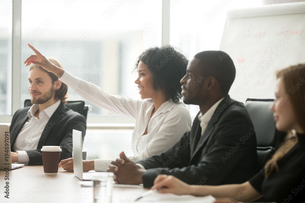 African woman raising hand to ask question at team training, curious black employee or conference seminar participant vote as volunteer at group office meeting with multiracial diverse businesspeople African woman raising hand to ask question at team training, curious black employee or conference seminar participant vote as volunteer at group office meeting with multiracial diverse businesspeople
