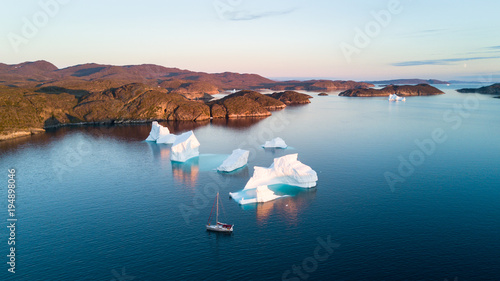 Air view to icebergs and yacht. Amazing Greenland.