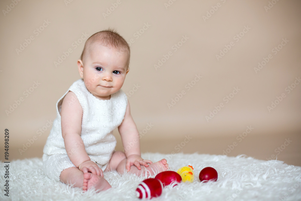 Cute little toddler baby boy, playing with colorful easter eggs and little decorative ducks Cute little toddler baby boy, playing with colorful easter eggs and little decorative ducks