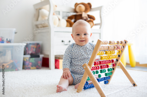 Cute little baby boy, playing with abacus at home