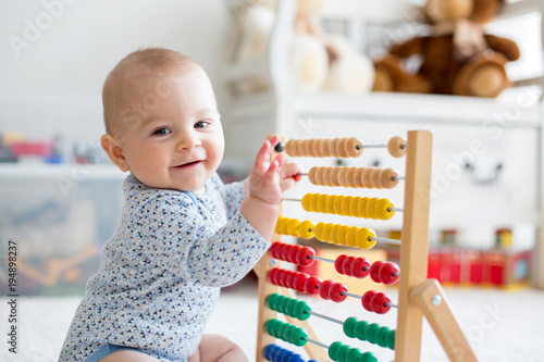 Fototapeta Cute little baby boy, playing with abacus at home