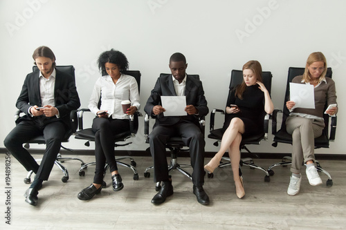 Bild auf Leinwand Nervous applicants preparing for employment interview sitting on chairs in queue