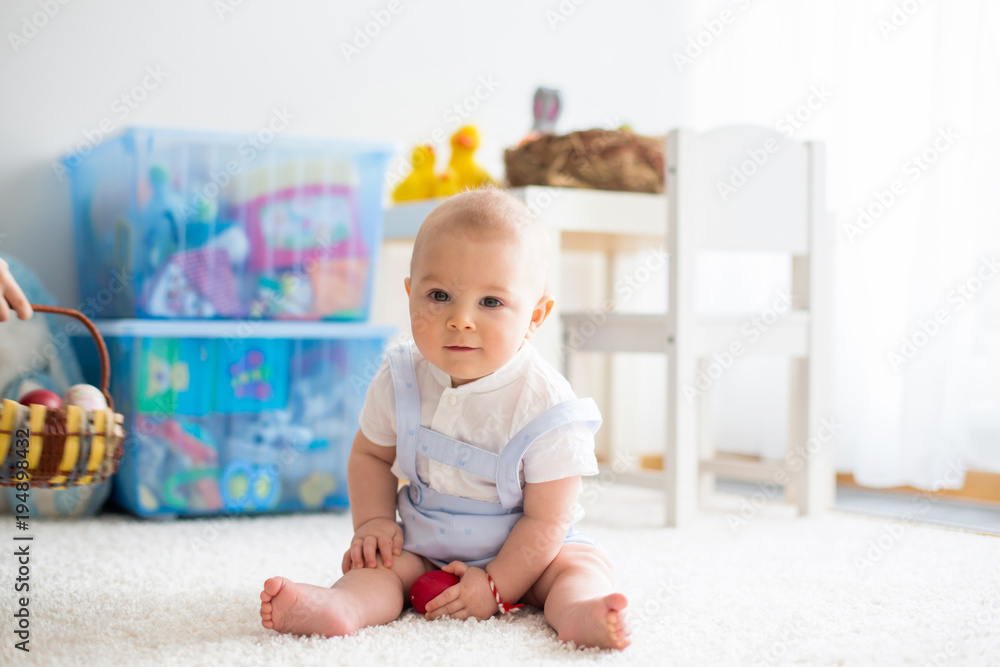 Cute little toddler child, baby boy, in sunny living room playing with Easter chocolate bunny Cute little toddler child, baby boy, in sunny living room playing with Easter chocolate bunny