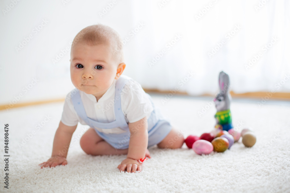 Cute little toddler child, baby boy, in sunny living room playing with Easter chocolate bunny Cute little toddler child, baby boy, in sunny living room playing with Easter chocolate bunny